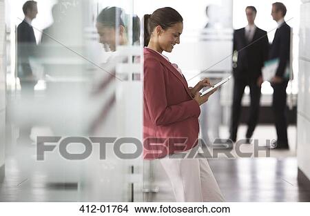 Businesswoman using digital tablet in office hallway View Large Photo Image Picture - Businesswoman using digital tablet in office hallway. Fotosearch