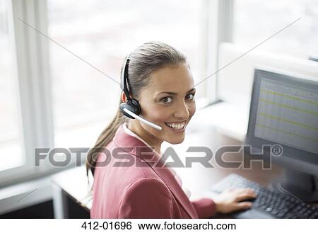 Businesswoman wearing headset at desk View Large Photo Image Stock Photograph - Businesswoman wearing headset at desk. Fotosearch