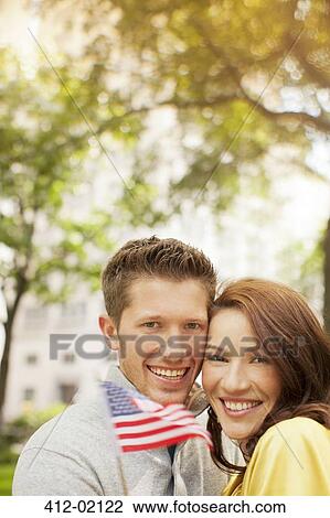 Couple waving American flag in urban park View Large Photo Image Stock Image - Couple waving American flag in urban park. Fotosearch
