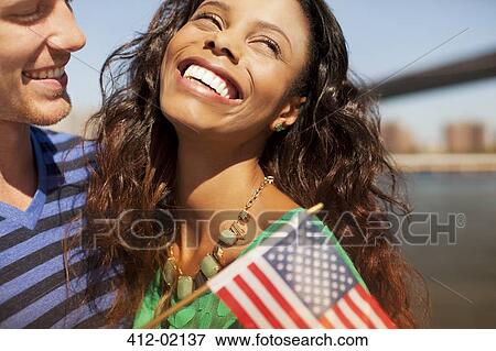 Stock Photo - Couple with American flag by city cityscape. Fotosearch