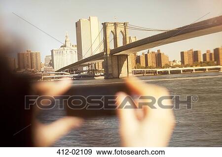 Stock Photo - Hands taking picture of urban bridge and cityscape. Fotosearch