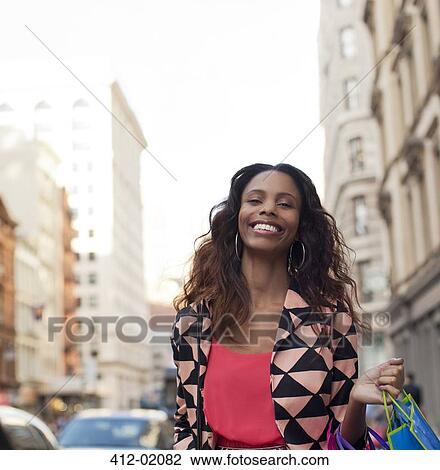 Stock Image - Smiling woman walking on city street. Fotosearch