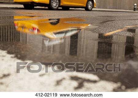Taxi reflected in puddle on city street View Large Photo Image Stock Photo - Taxi reflected in puddle on city street . Fotosearch