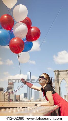 Woman holding bunch of balloons on urban bridge View Large Photo Image Stock Image - Woman holding bunch of balloons on urban bridge. Fotosearch