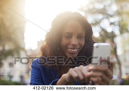 Stock Photograph - Woman using cell phone in urban park. Fotosearch
