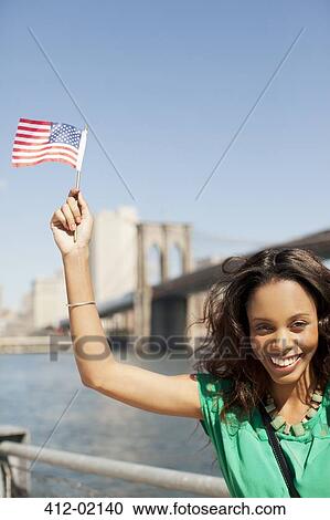 Woman waving American flag at urban waterfront View Large Photo Image Stock Image - Woman waving American flag at urban waterfront. Fotosearch
