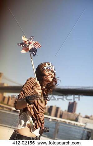 Stock Photography - Woman with novelty sunglasses and pinwheel by city bridge. Fotosearch