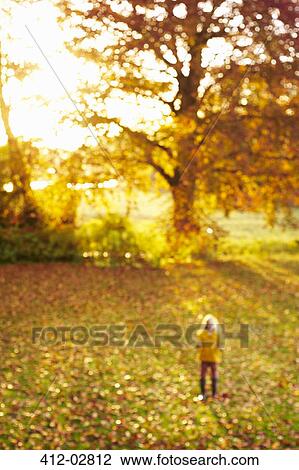 Stock Image - Blurred view of girl standing in meadow. Fotosearch