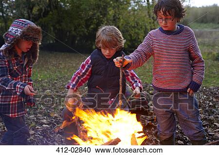Stock Image - Boys building bonfire outdoors. Fotosearch