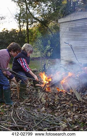 Stock Photo - Boys building bonfire outdoors. Fotosearch