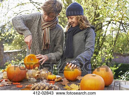 Stock Image - Children carving pumpkins together outdoors. Fotosearch