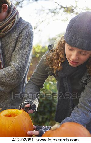 Stock Image - Children carving pumpkins together outdoors. Fotosearch