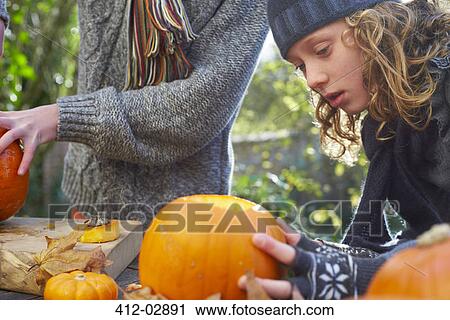 Stock Image - Children carving pumpkins together outdoors. Fotosearch