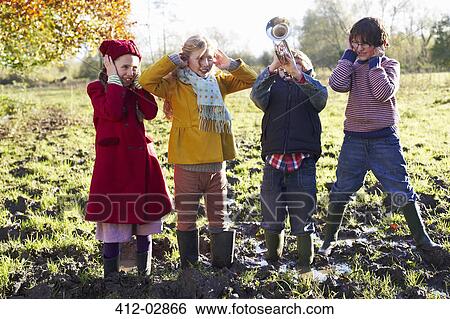 Stock Photograph - Children covering their ears as boy plays trumpet. Fotosearch