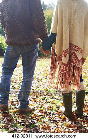 Couple holding hands in autumn leaves View Large Photo Image Stock Image - Couple holding hands in autumn leaves. Fotosearch