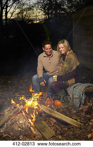 Couple talking around campfire at night View Large Photo Image Stock Image - Couple talking around campfire at night. Fotosearch