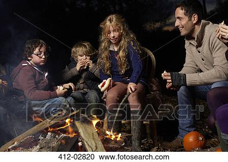 Family eating around campfire at night View Large Photo Image Stock Image - Family eating around campfire at night. Fotosearch