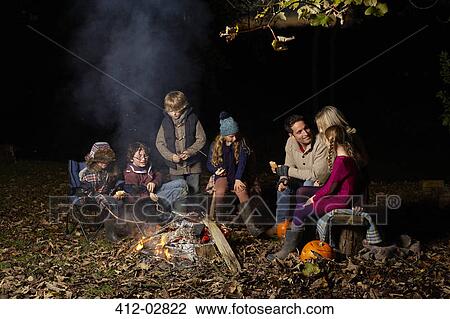 Family eating around campfire at night View Large Photo Image Stock Image - Family eating around campfire at night. Fotosearch