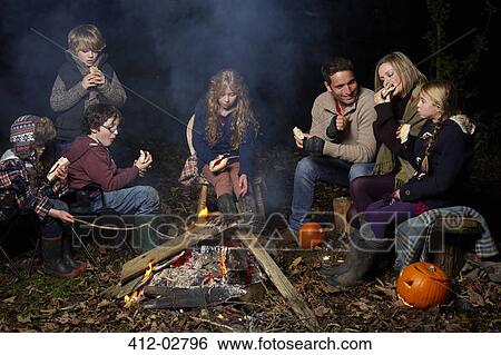 Family eating around campfire at night View Large Photo Image Stock Photograph - Family eating around campfire at night. Fotosearch