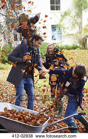 Family playing in autumn leaves View Large Photo Image Stock Photo - Family playing in autumn leaves. Fotosearch
