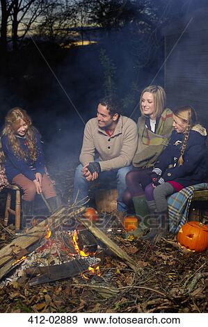Family relaxing around campfire at night View Large Photo Image Stock Photo - Family relaxing around campfire at night. Fotosearch