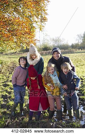 Stock Photography - Family smiling together in muddy field. Fotosearch