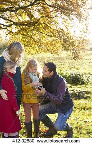 Stock Image - Family using cell phone together outdoors. Fotosearch