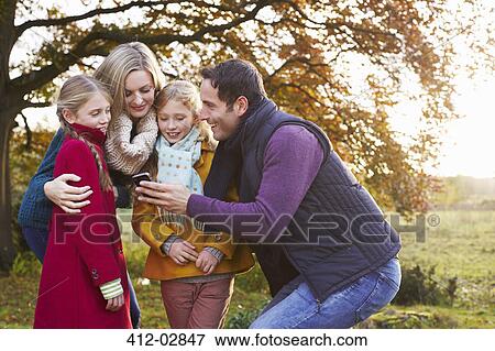 Stock Photo - Family using cell phone together outdoors. Fotosearch