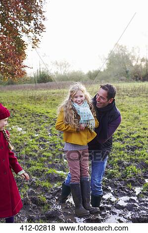 Father and daughter laughing in muddy field View Large Photo Image Stock Photo - Father and daughter laughing in muddy field. Fotosearch