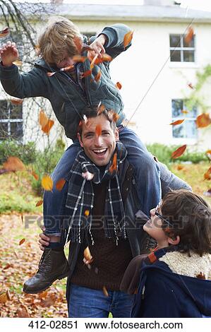 Stock Image - Father and son playing in autumn leaves. Fotosearch
