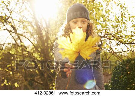 Girl holding autumn leaf outdoors View Large Photo Image Stock Image - Girl holding autumn leaf outdoors. Fotosearch