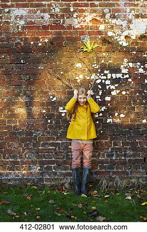 Stock Image - Girl holding branches like antlers outdoors. Fotosearch