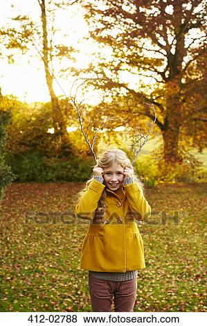 Girl holding branches like antlers View Large Photo Image Stock Photo - Girl holding branches like antlers. Fotosearch