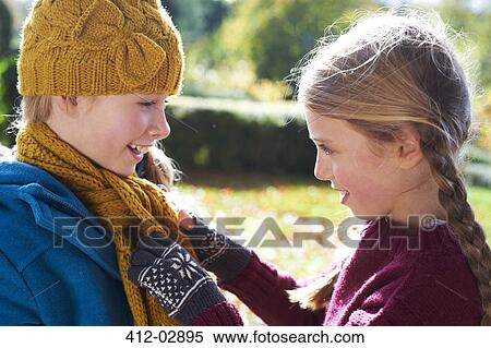 Girl tying sister's scarf outdoors View Large Photo Image Stock Photography - Girl tying sister's scarf outdoors. Fotosearch