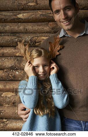 Girl using leaves as antlers with smiling father View Large Photo Image Stock Photograph - Girl using leaves as antlers with smiling father. Fotosearch