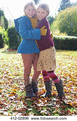 Girls hugging in autumn leaves View Large Photo Image Stock Photograph - Girls hugging in autumn leaves. Fotosearch