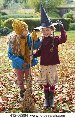 Picture - Girls playing with witch's hat and broom outdoors. Fotosearch