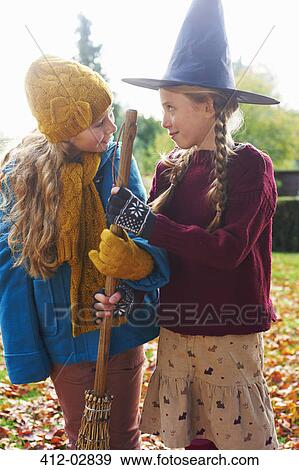 Stock Photo - Girls playing with witch's hat and broom outdoors. Fotosearch