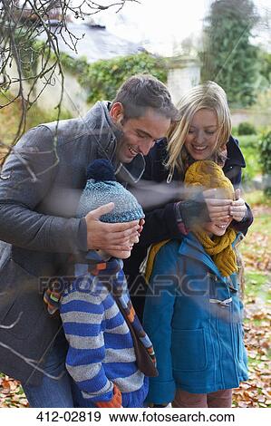 Stock Photo - Parents covering children's eyes outdoors. Fotosearch