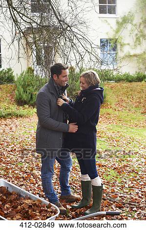 Stock Photo - Smiling couple standing in autumn leaves. Fotosearch
