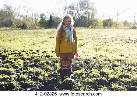 Smiling girl standing in muddy field View Large Photo Image Stock Photograph - Smiling girl standing in muddy field. Fotosearch