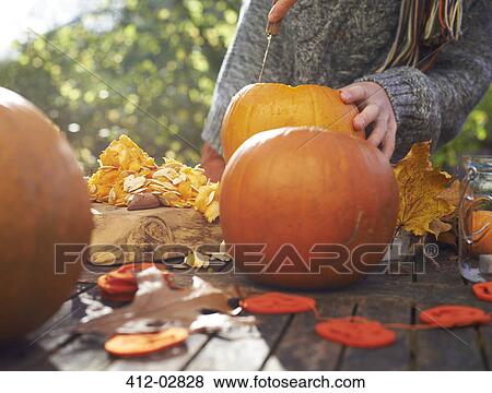 Stock Photo - Teenage boy carving pumpkins outdoors. Fotosearch