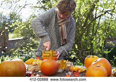 Stock Photo - Teenage boy carving pumpkins outdoors. Fotosearch