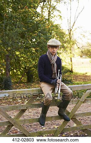 Teenage boy holding trumpet on wooden fence View Large Photo Image Stock Image - Teenage boy holding trumpet on wooden fence. Fotosearch