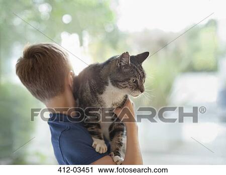 Boy holding cat indoors View Large Photo Image Stock Image - Boy holding cat indoors. Fotosearch