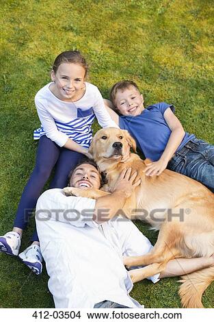 Family relaxing with dog on lawn View Large Photo Image Picture - Family relaxing with dog on lawn. Fotosearch