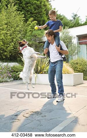 Stock Photo - Father and son playing with dog outdoors. Fotosearch