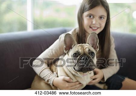 Stock Photograph - Girl relaxing dog on sofa. Fotosearch
