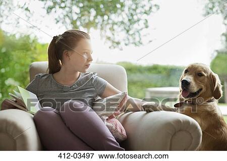 Stock Photo - Girl relaxing with dog in armchair. Fotosearch