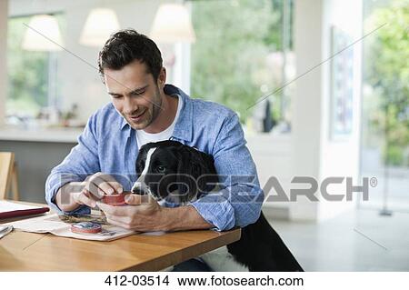 Man feeding dog at kitchen table View Large Photo Image Picture - Man feeding dog at kitchen table. Fotosearch
